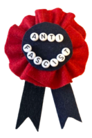 A ribbon made of black and red felt, with beads that spell out 'anti-fascist' in all-caps.